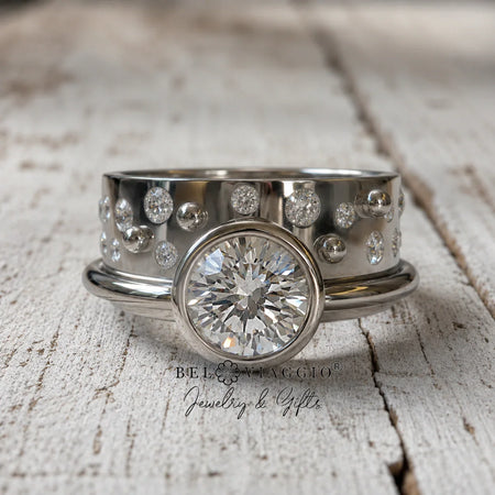 Custom engagement ring with round diamond center and pavé side stones on rustic wood