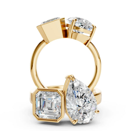 Gold engagement rings with pear, emerald, and round cut diamonds on white background