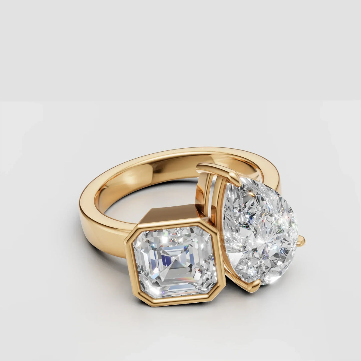 Yellow gold ring with pear and asscher cut diamonds on white background