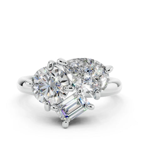 Three-stone diamond engagement ring with round, oval, and emerald-cut diamonds on white gold band