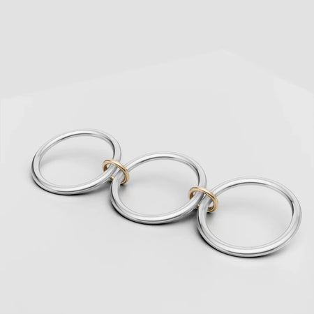 Three large silver rings linked by small gold rings on a white background, modern jewelry design