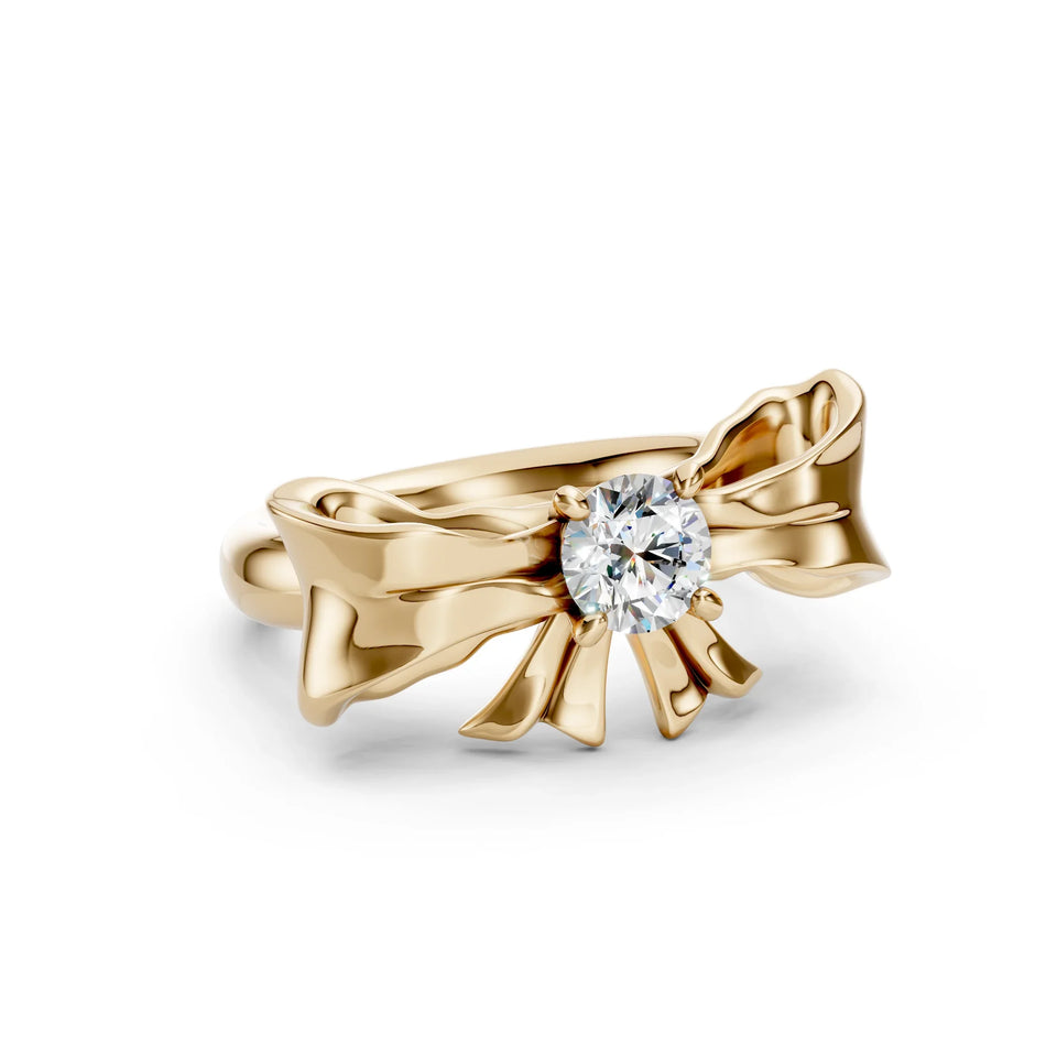 Gold bow-shaped engagement ring with a round brilliant diamond center stone