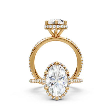 Oval diamond halo engagement ring with yellow gold band, pavé accents, and prong setting