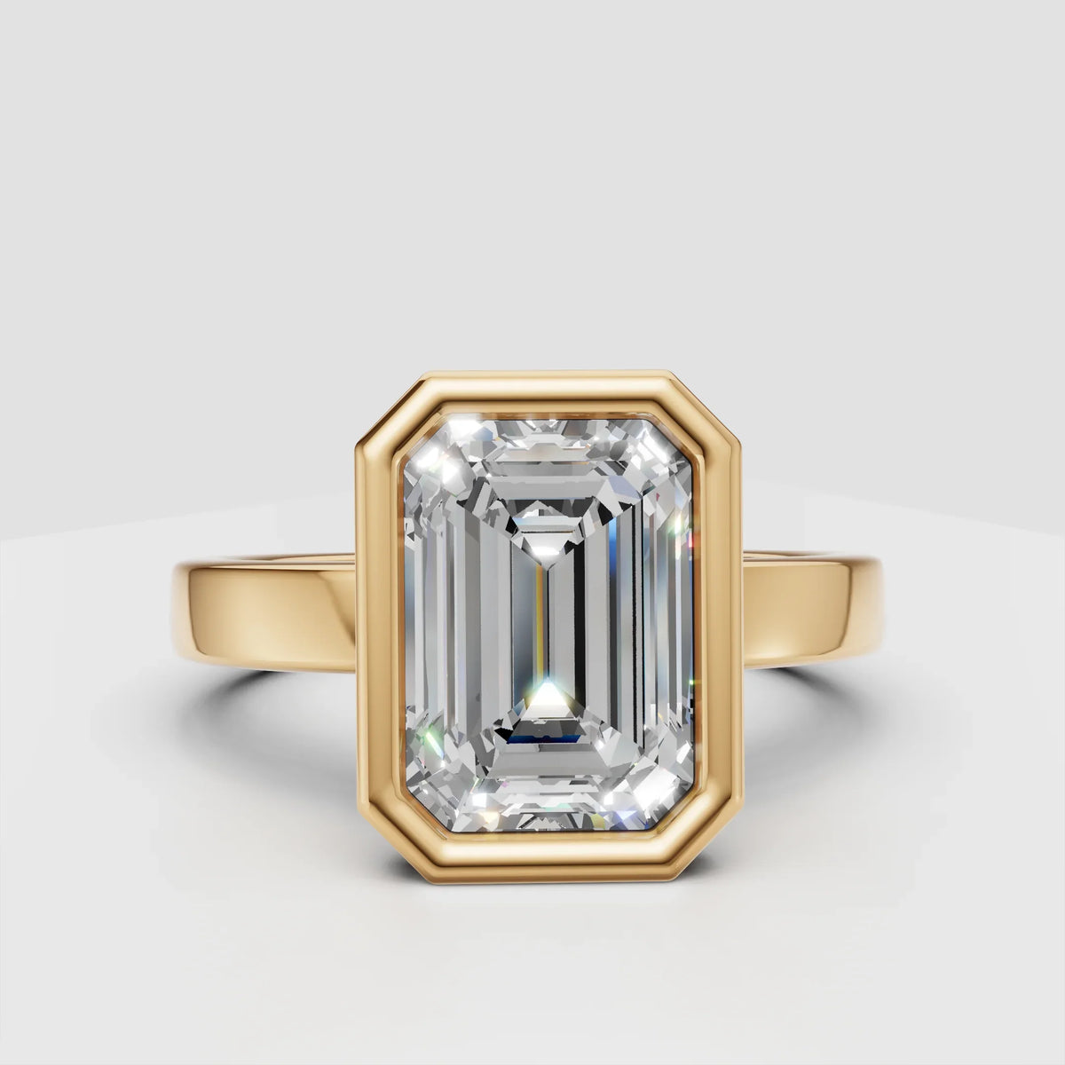 Emerald cut diamond engagement ring with yellow gold setting on white background
