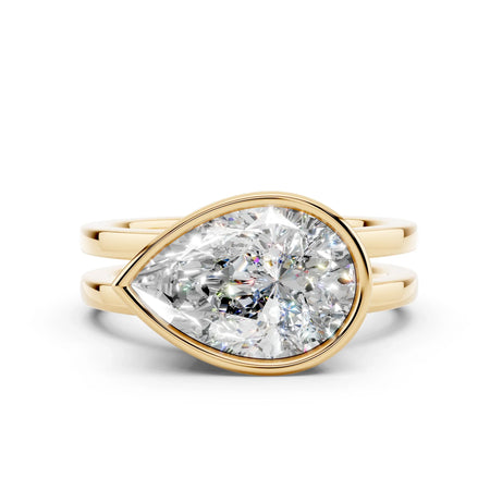 Pear-shaped diamond engagement ring with yellow gold double band on white background
