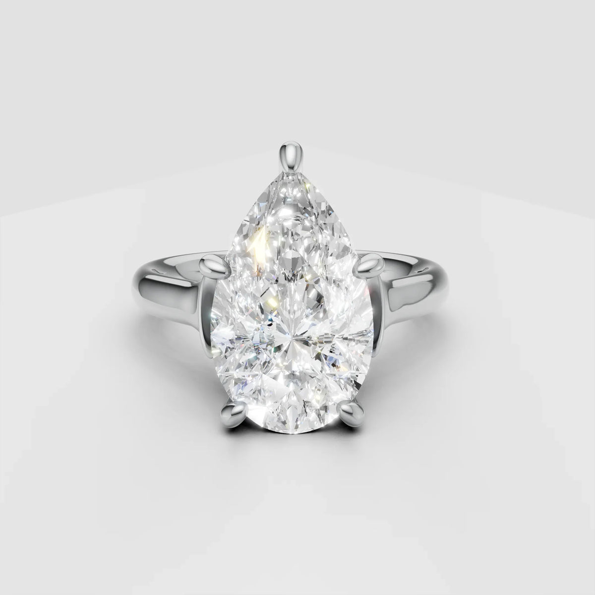 Pear-shaped diamond engagement ring with white gold band on light background