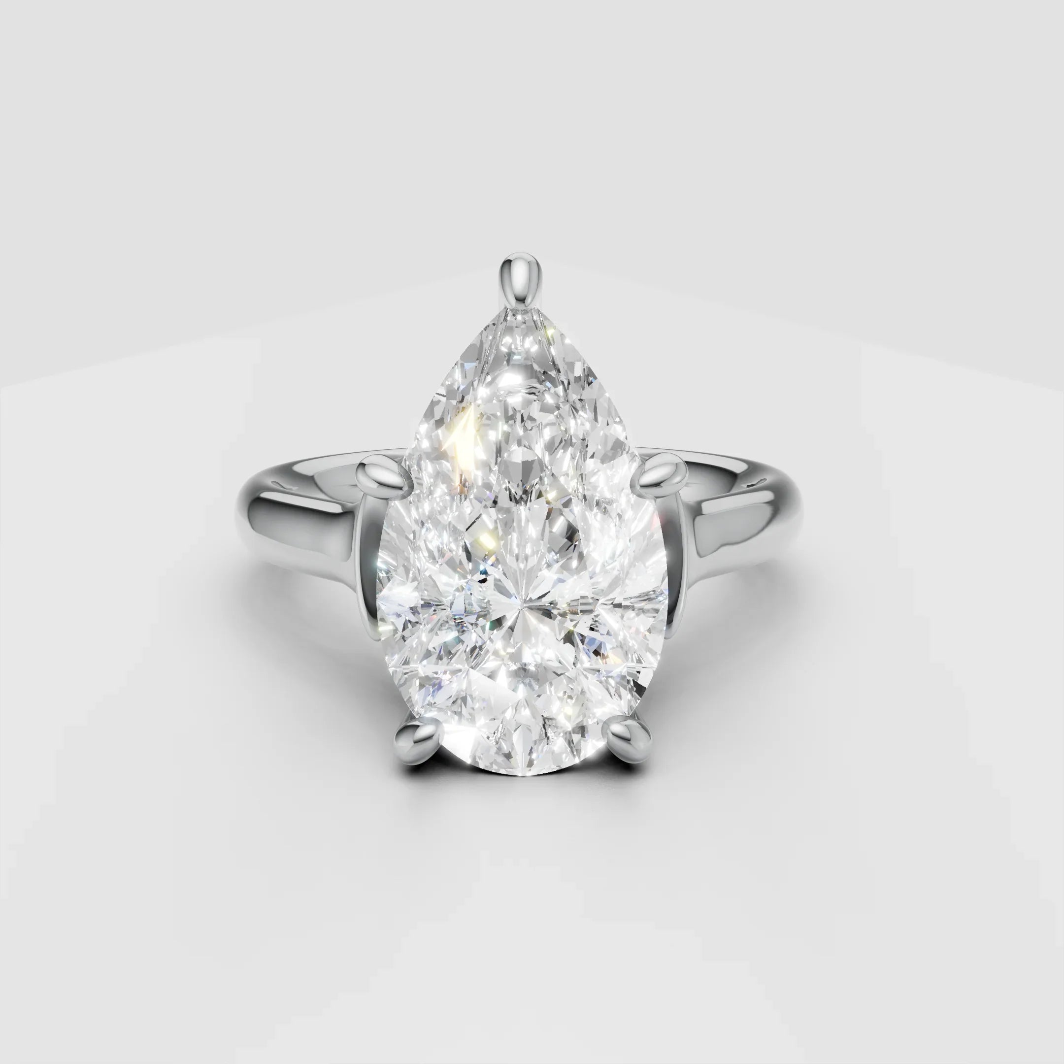 Pear-shaped diamond engagement ring with white gold band on light background