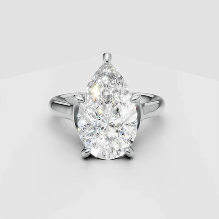 Pear-shaped diamond engagement ring with white gold band on light background