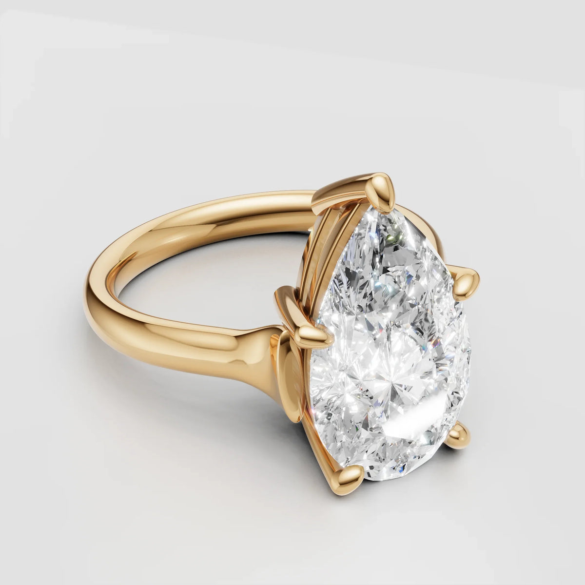 Gold engagement ring with a large pear-shaped diamond center stone on a plain band