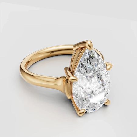 Gold engagement ring with a large pear-shaped diamond center stone on a plain band