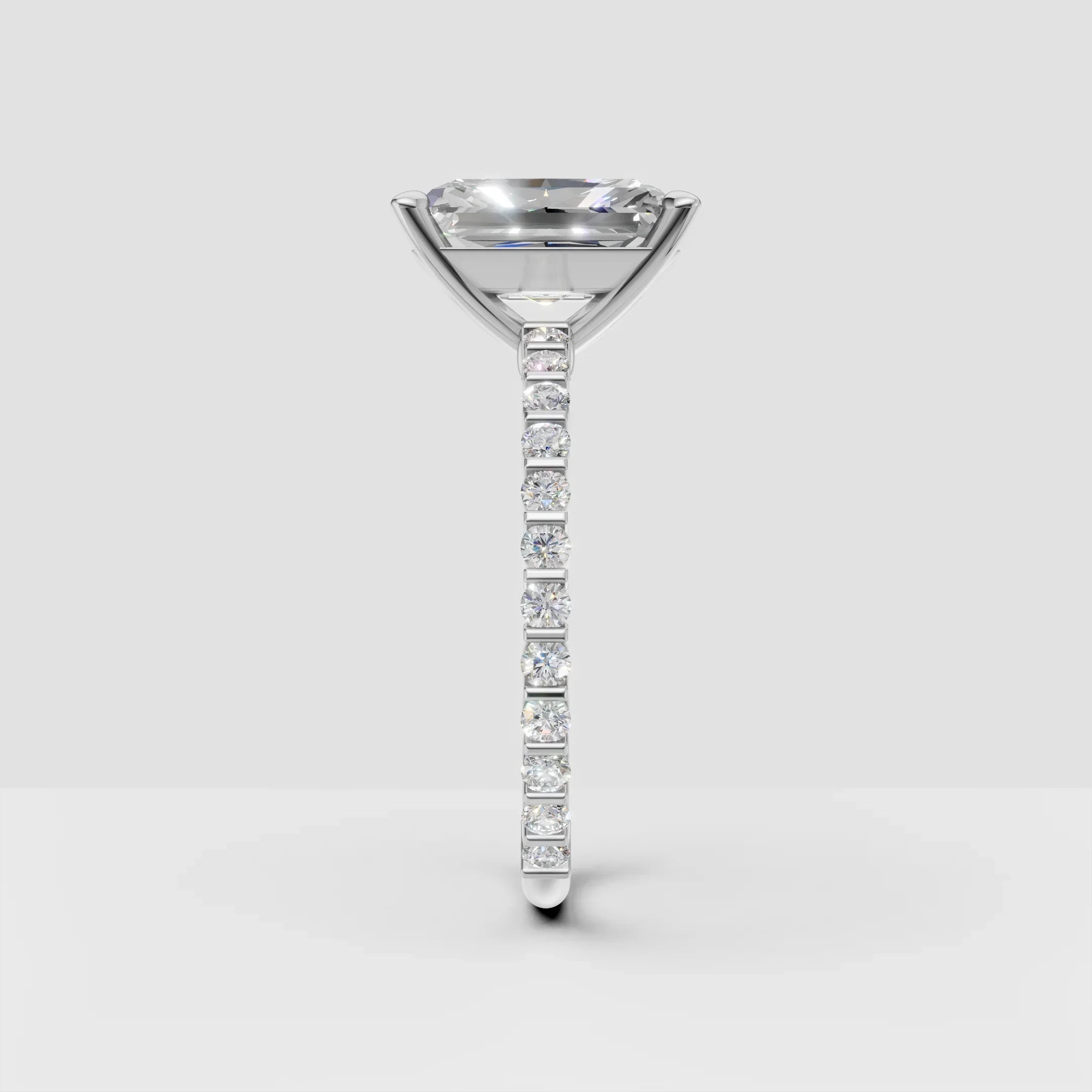 Side view of a white gold engagement ring with a solitaire diamond and pavé band