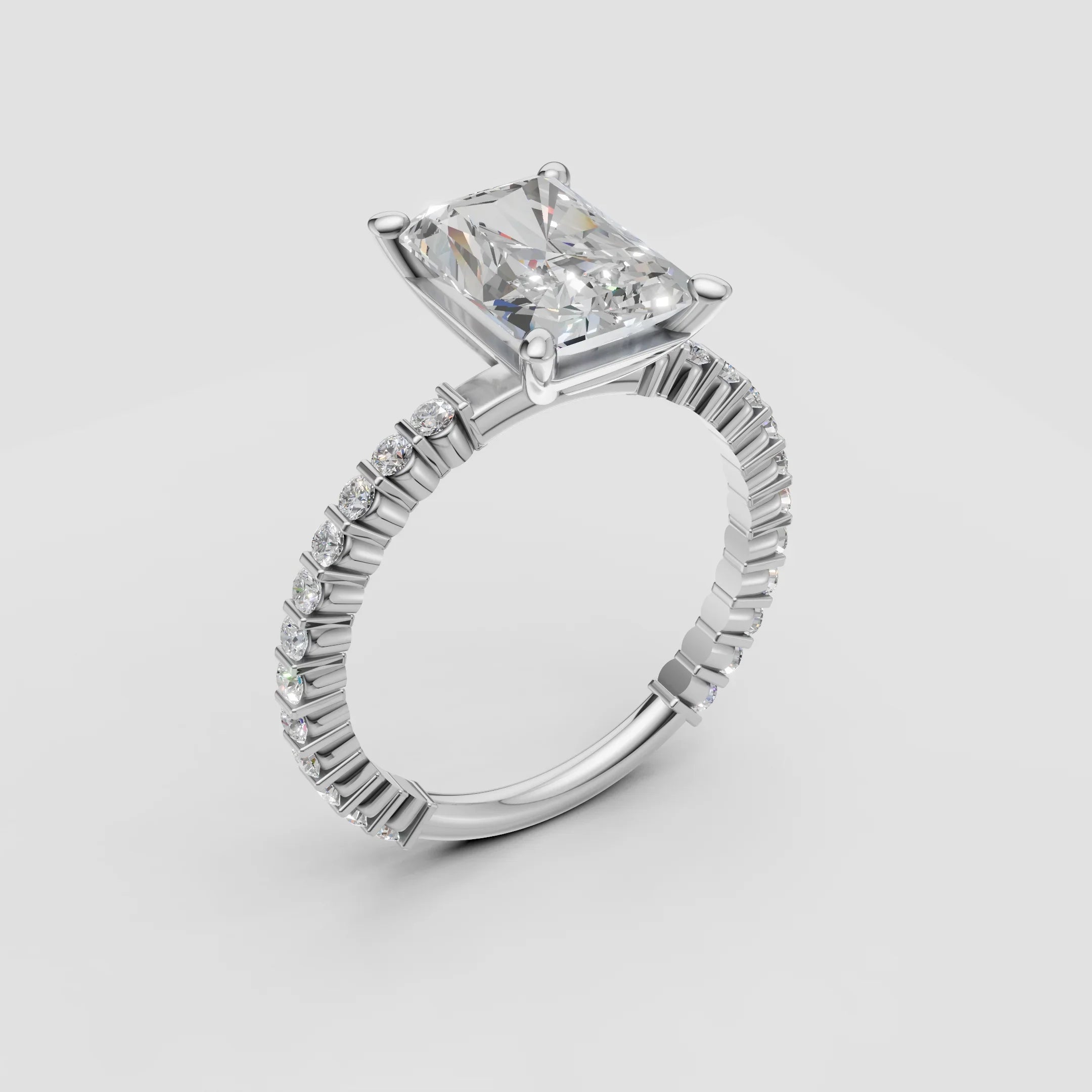 Radiant cut diamond engagement ring with pavé band in white gold on white background