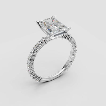 Radiant cut diamond engagement ring with pavé band in white gold on white background