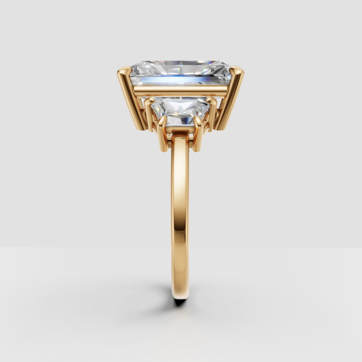 Gold engagement ring with rectangular center diamond and side stones, prong setting