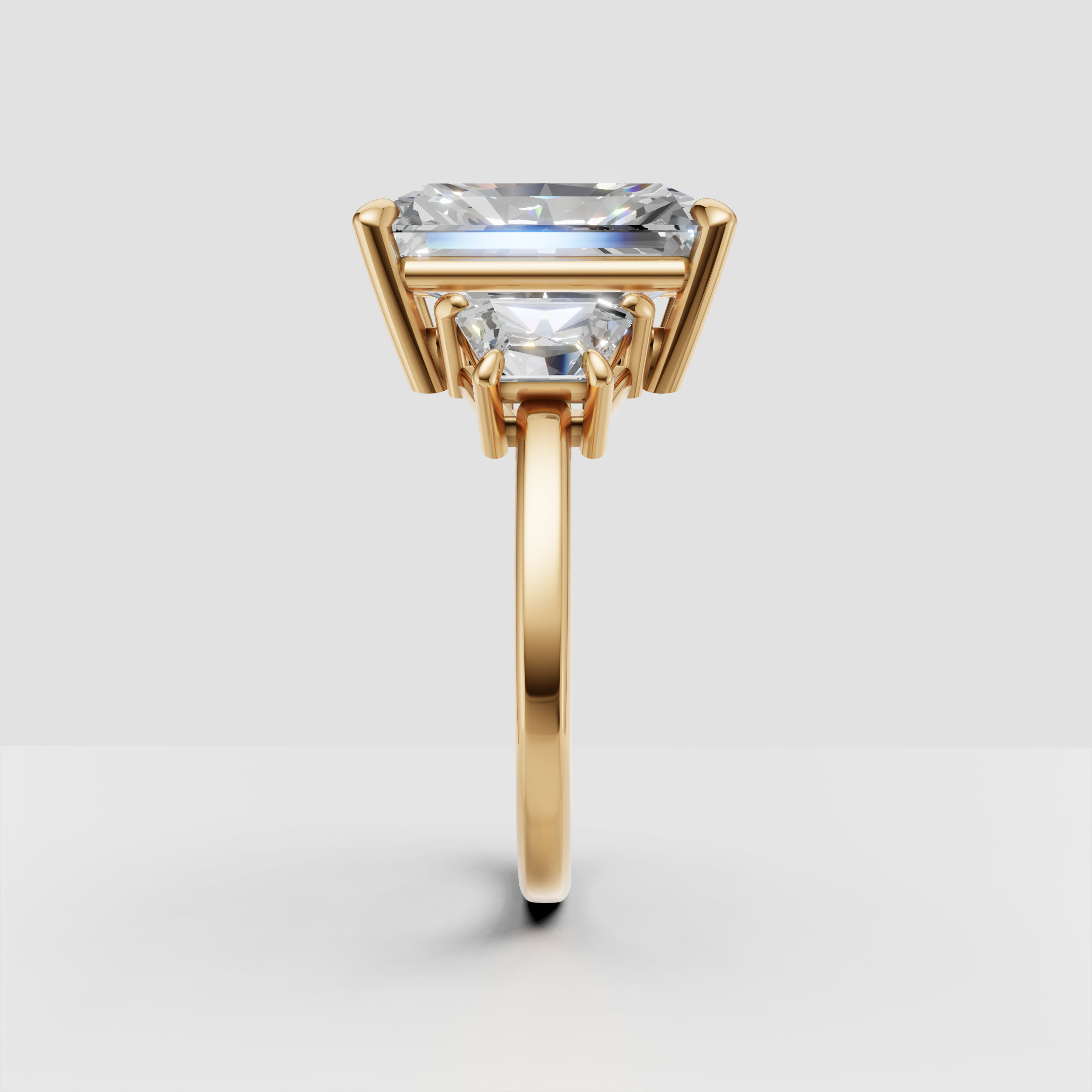 Gold engagement ring with rectangular center diamond and side stones, prong setting