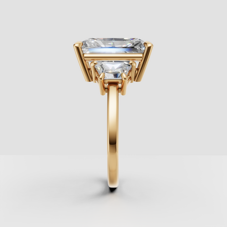 Gold engagement ring with rectangular center diamond and side stones, prong setting
