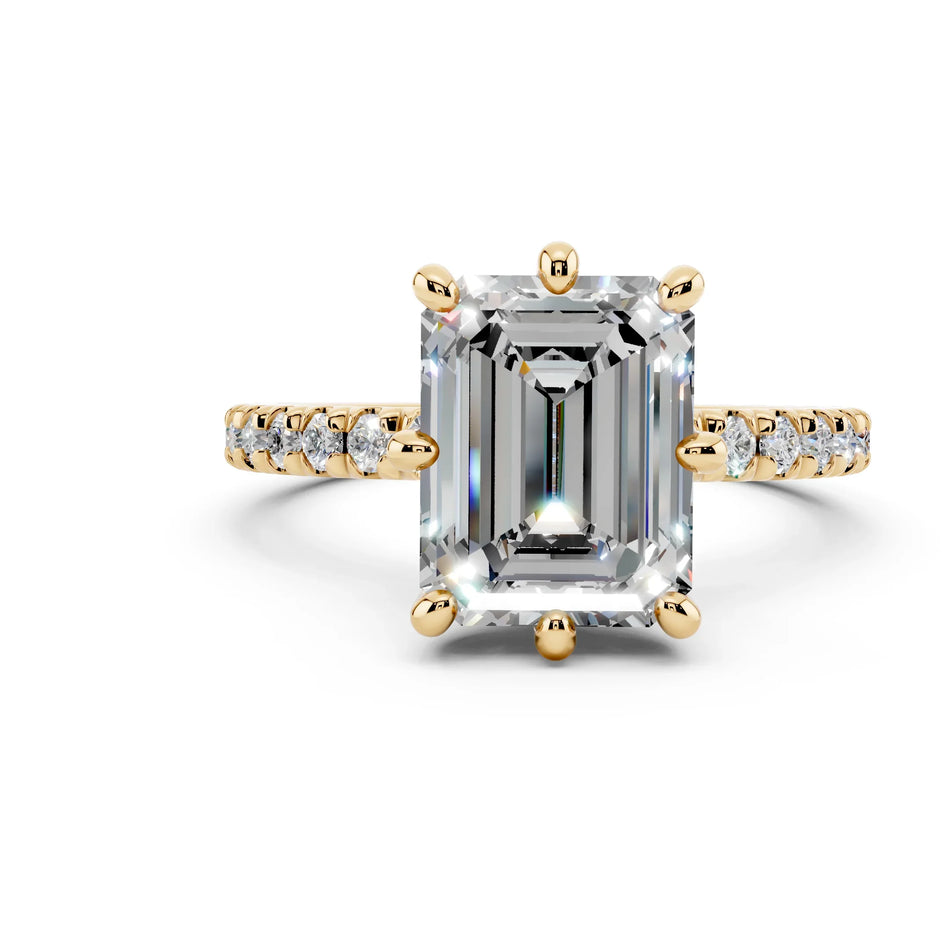 Emerald-cut diamond engagement ring with gold band and pavé side stones on white background