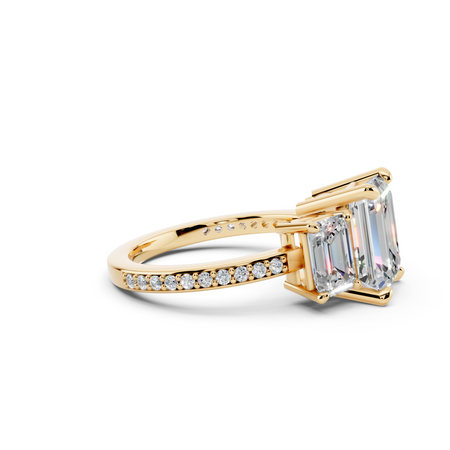 Three stone emerald-cut diamond engagement ring with pavé band in yellow gold