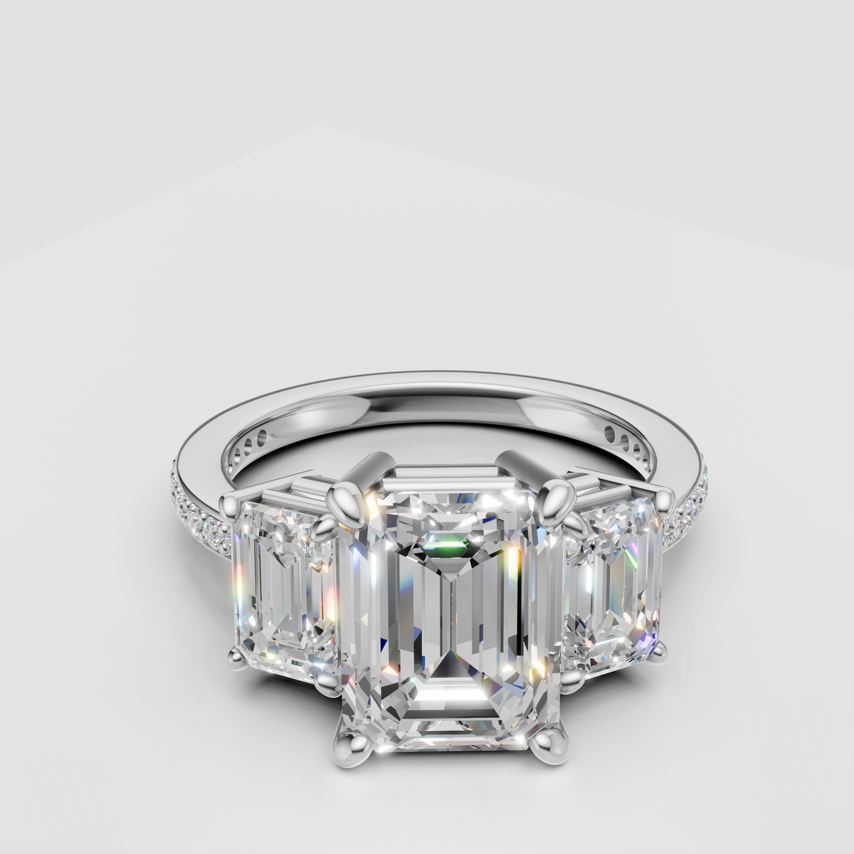 Three stone emerald cut diamond engagement ring with a pavé band in white gold