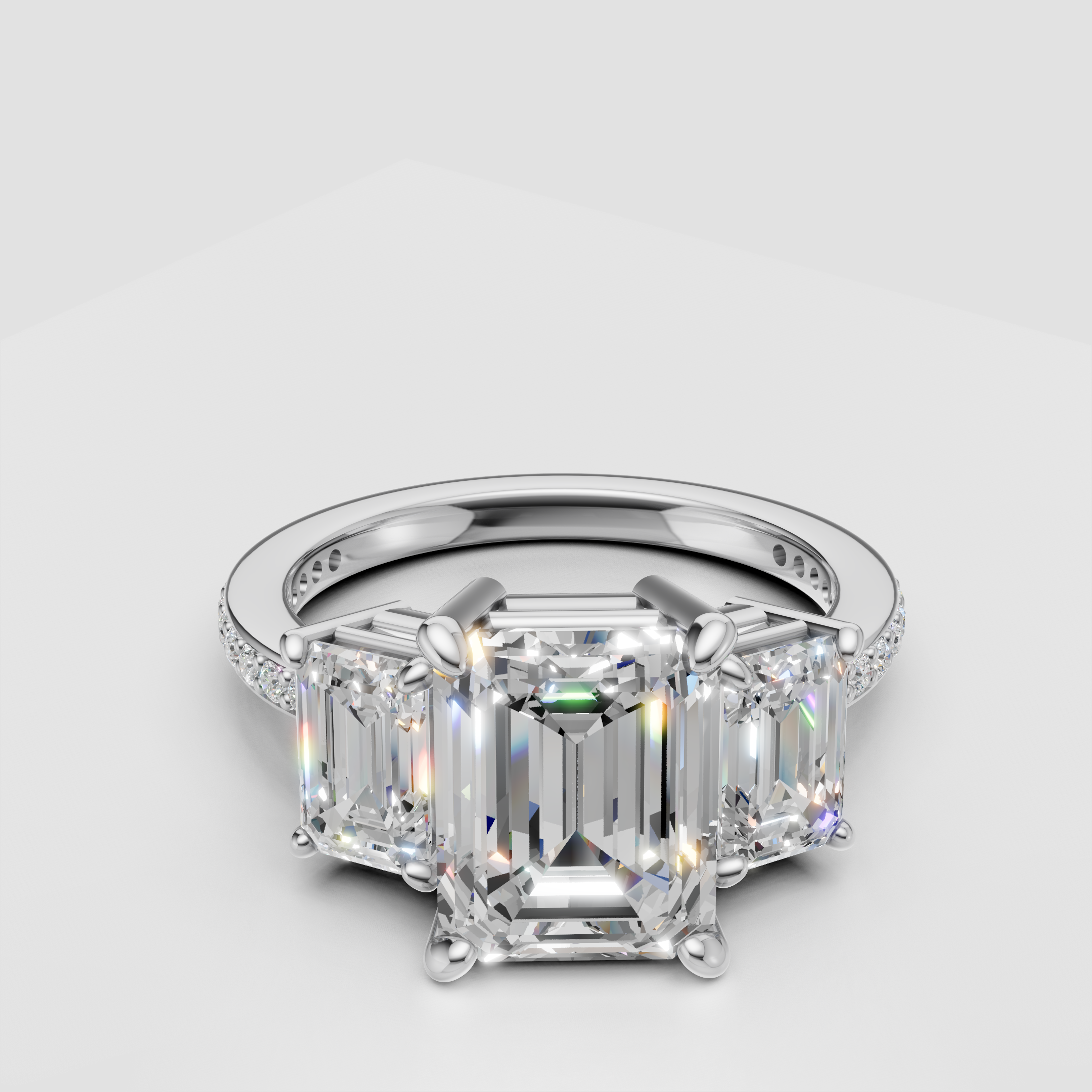 Three stone emerald cut diamond engagement ring with a pavé band in white gold