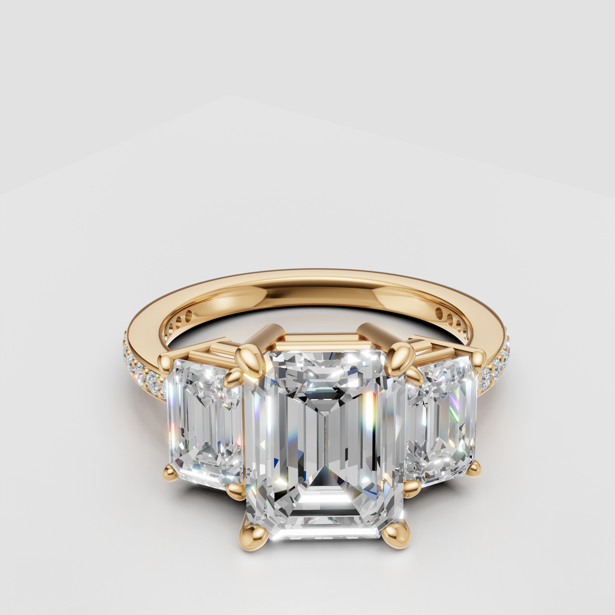 Three stone emerald cut diamond engagement ring with gold band and pavé accents