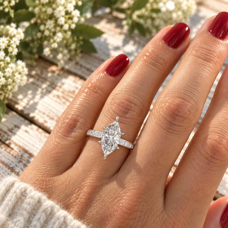 Marquise diamond engagement ring with baguette setting on a hand with red nails
