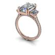 Rose gold engagement ring with emerald-cut center stone, two side stones, and pavé diamond band