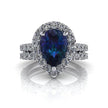 Pear-shaped alexandrite halo engagement ring with diamond bridal set on white background