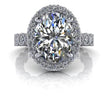 Oval halo diamond engagement ring with pavé band on white background